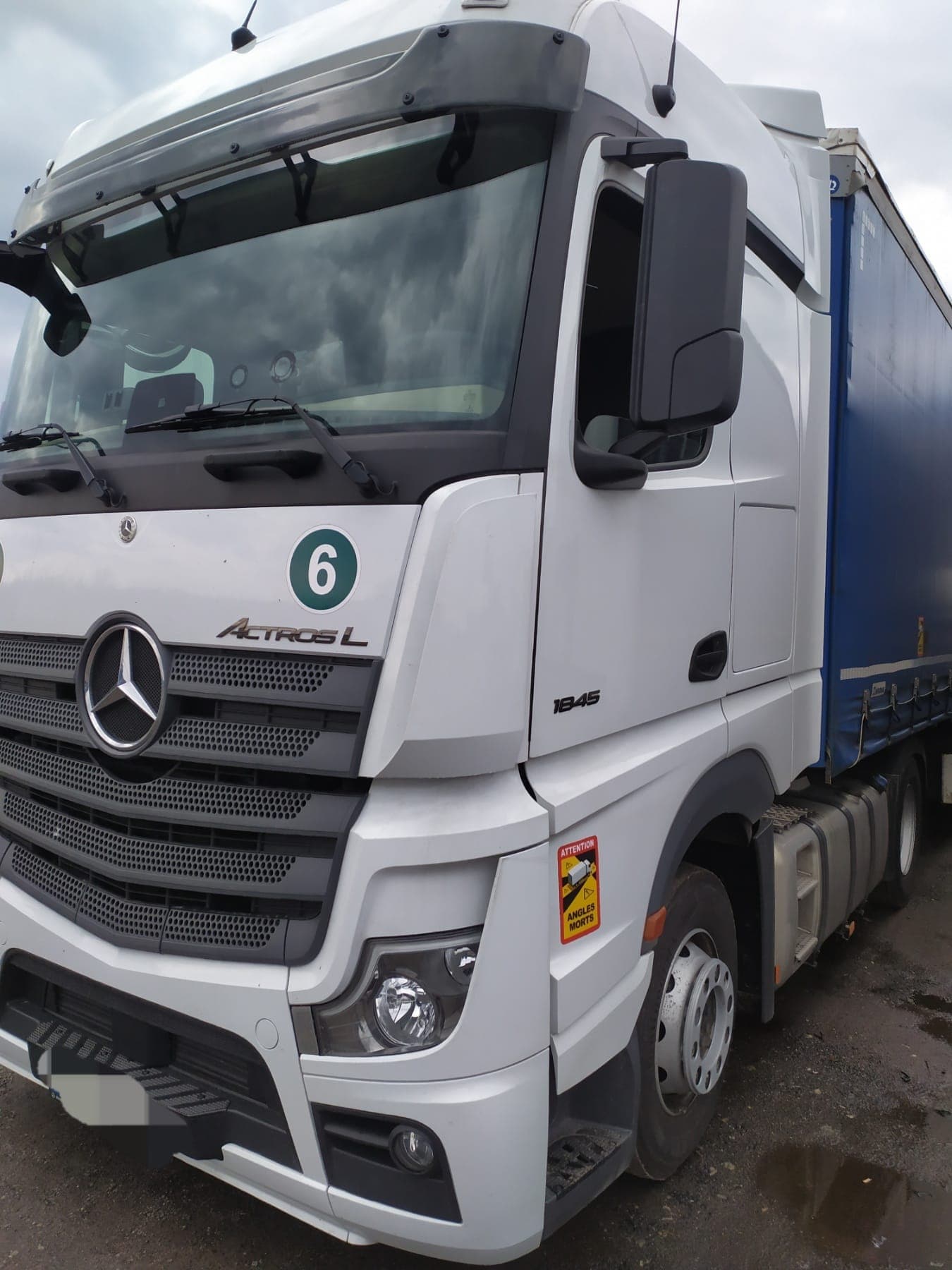 White Actros L unit 6 coupled to a blue curtain-side trailer