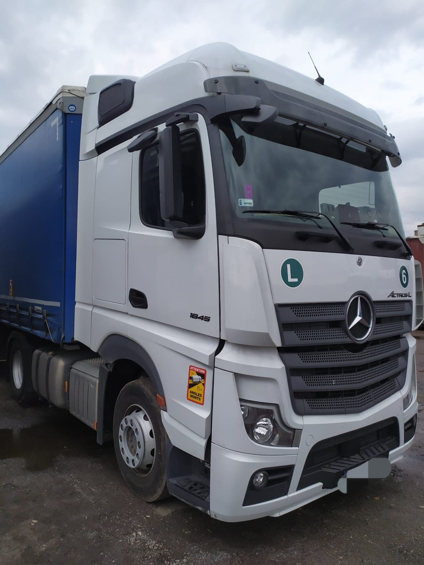 White Actros L unit 6 with a blue curtain-side trailer ready for loading