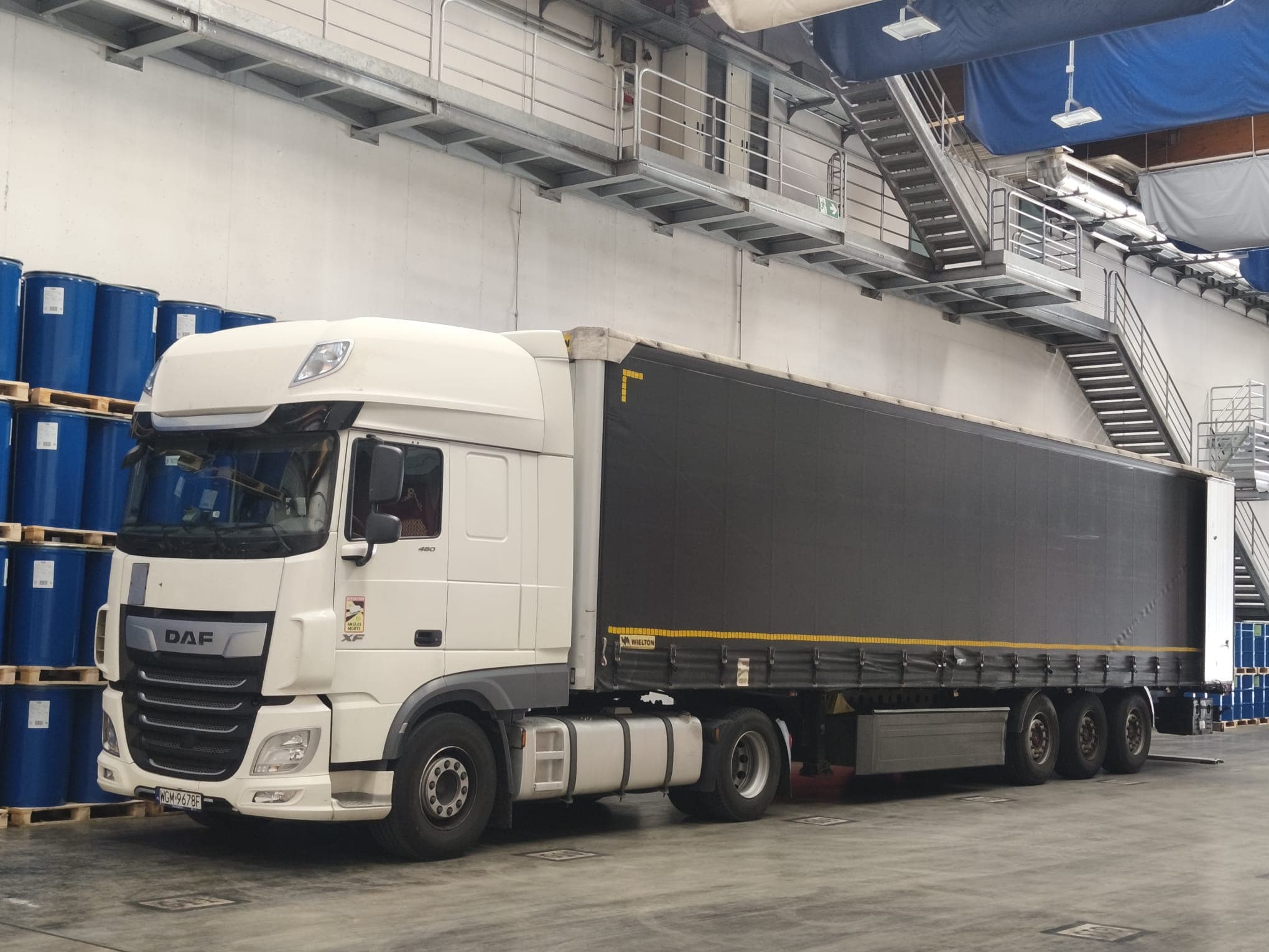 White DAF XF with a black Wielton curtain-side trailer in the warehouse