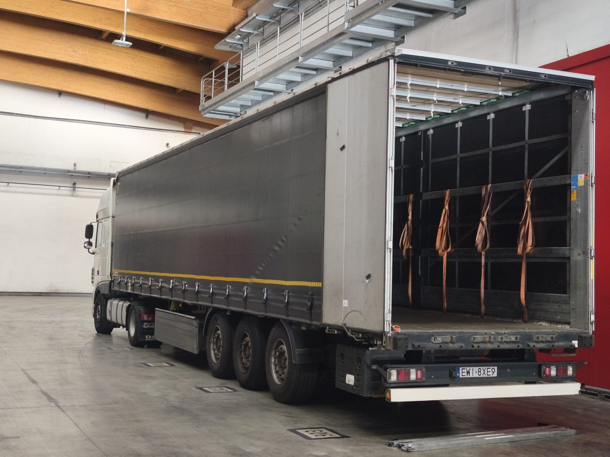 Open rear of a curtain-side trailer inside the warehouse loading bay