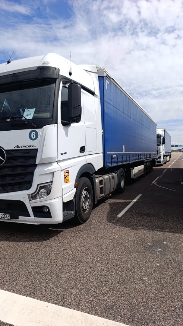 White Mercedes-Benz Actros L unit 6 with a blue curtain-side trailer outdoors