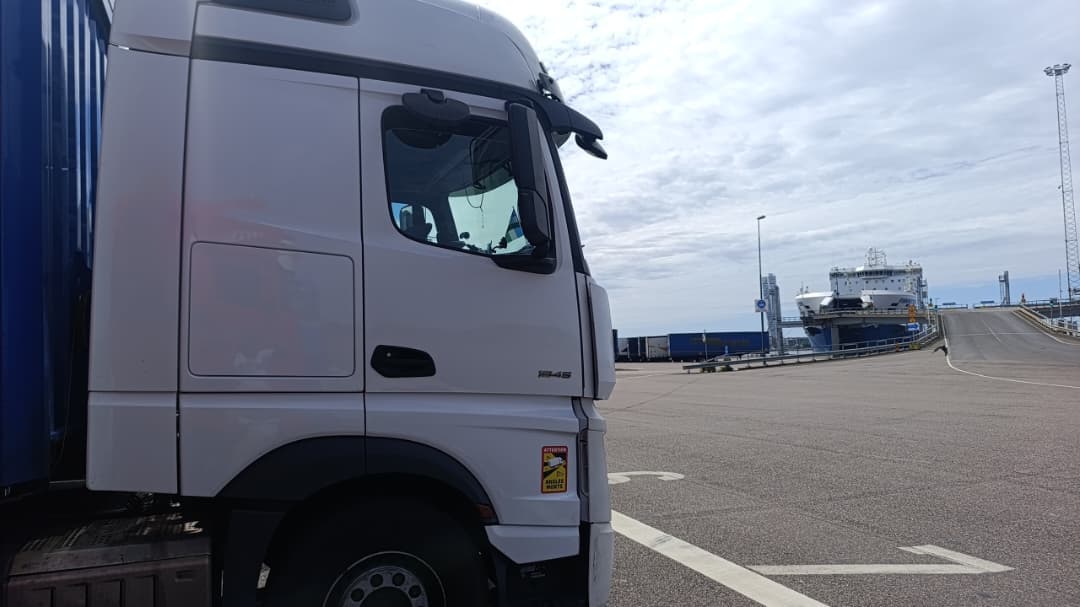 Side view of a white Actros 1845 with a ferry docked in the background